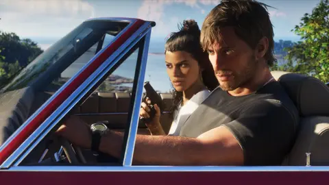 Jason at the wheel of a convertible on a coast road while Lucia holds a pistol upright beside him