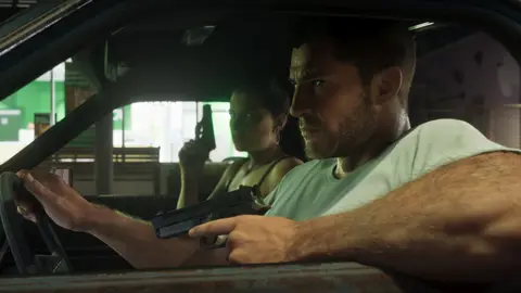 Jason at the wheel with a pistol while Lucia covers the window from the passenger seat at night