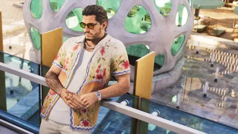 Jason in a floral shirt and sunglasses leaning on a glass balcony above a hotel pool