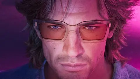 Close-up of Jason in tinted glasses under pink light, hair swept back