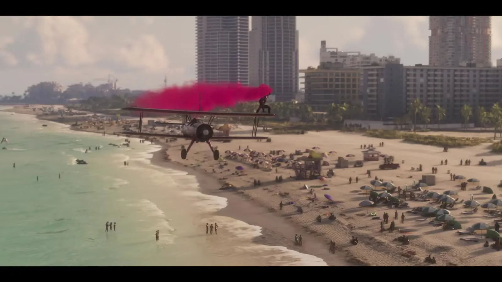 Ein Doppeldecker zieht pinken Rauch tief über einen vollen Strand, aus dem GTA 6 Launch Trailer
