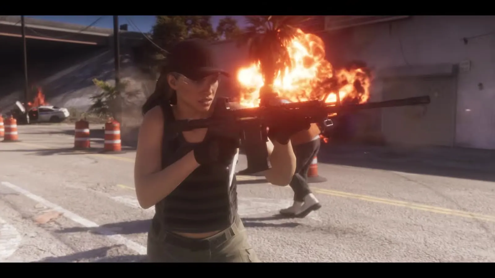 Lucia feuert bei einer Straßenschießerei neben einem brennenden Auto ein Sturmgewehr ab, aus dem GTA 6 Launch Trailer