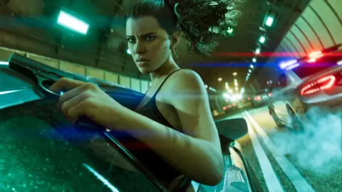 Lucia leaning out of a car window with a pistol in a lit tunnel, a police car closing in behind