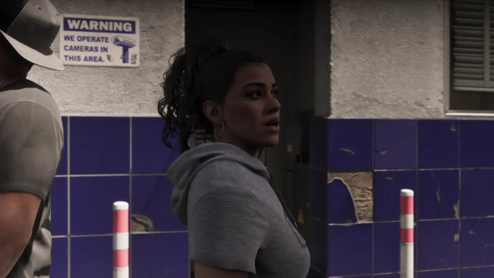 Lucia passing a wall sign warning that cameras operate in the area, from the GTA 6 Extended Look